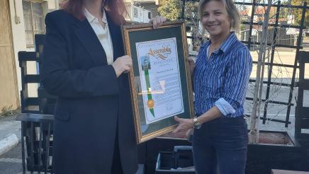 Assemblymember Friedman presents the owner of Romancing the Bean, Kerry Krull-Meadows, with a resolution honoring their 30 years of service.