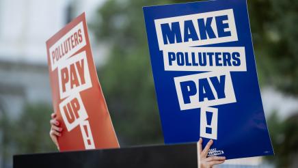 rally attendees holding signs that say Make Polluters Pay