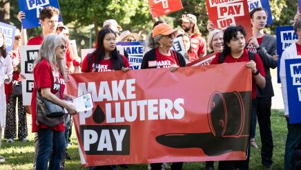 rally attendees holding sign that say Make Polluters Pay