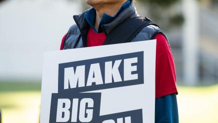 rally attendee holding sign that say Make Big Oil Pay