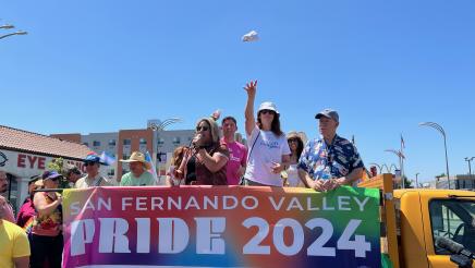 Assemblymember Laura Friedman throwing hats to the watching crowd